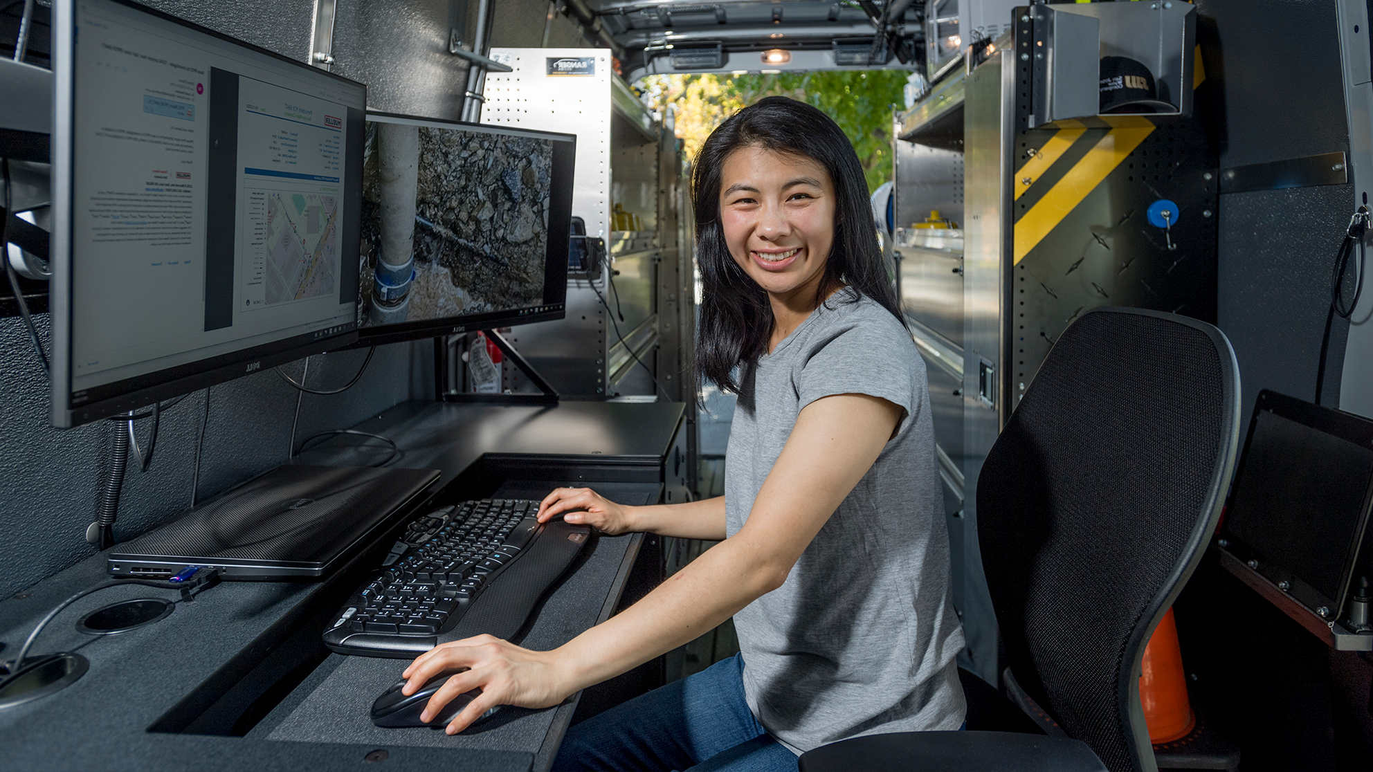 San Jose Water employee in front of monitors and smiling at the camera