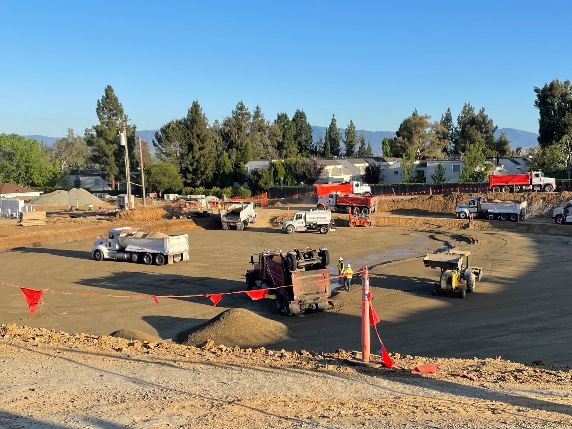 Heavy equipment removing excess soil from base of new tank