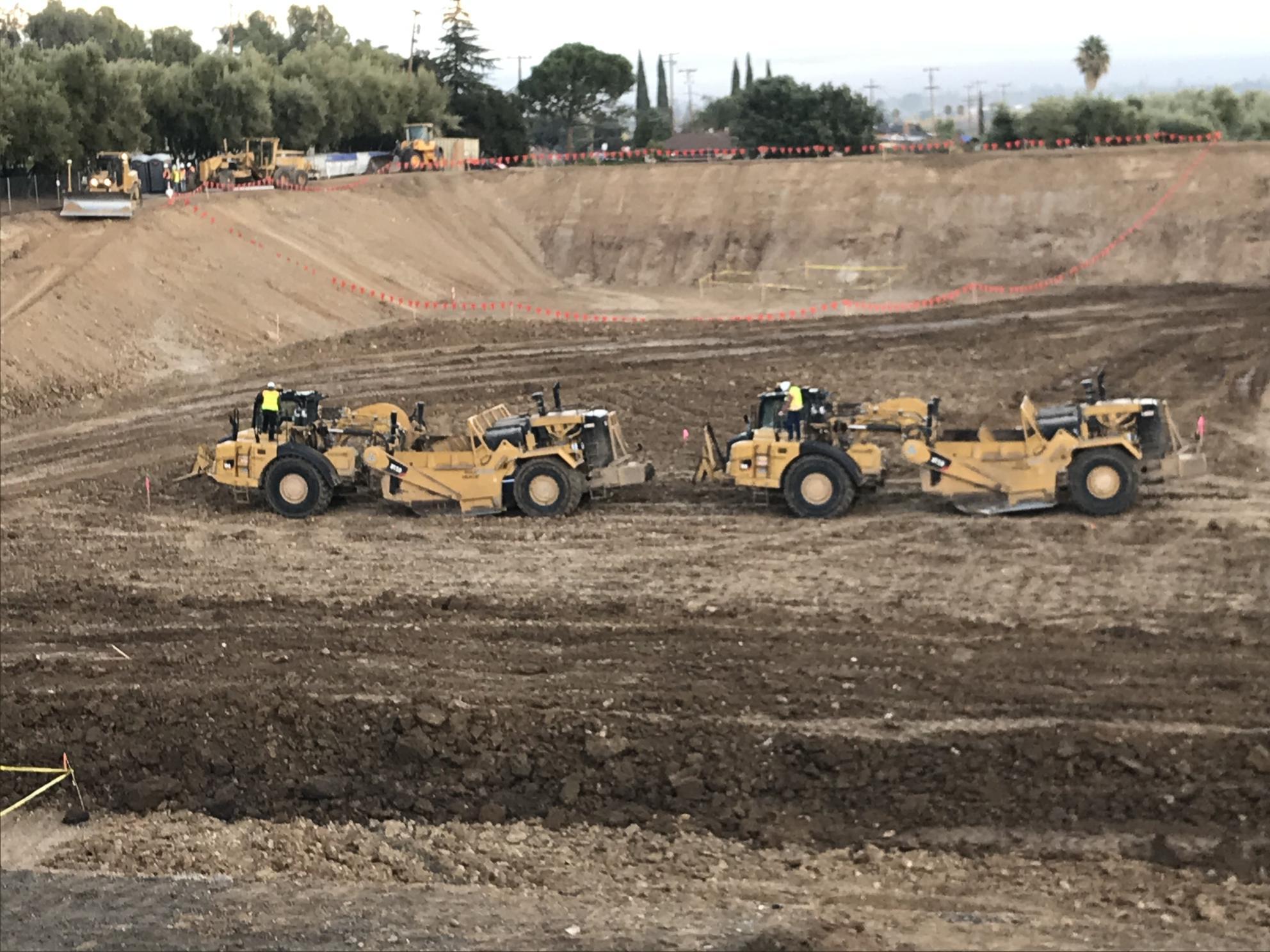 two pieces of heavy machinery in large hole